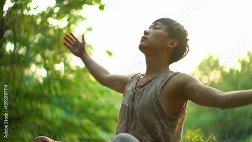 An ethnically ambiguous person in natural-fiber clothing meditates in a tranquil, sun-dappled forest or studio, rising gracefully towards an ethereal light. Crane video captures a profound spiritual