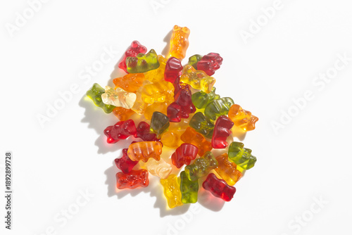 Colorful gummy bears pile on a white background, representing sweet treats and childhood
