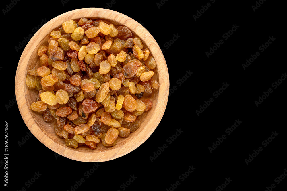Φωτογραφία Dry sweet raisins in a wooden saucer on a black background, close-up, top view