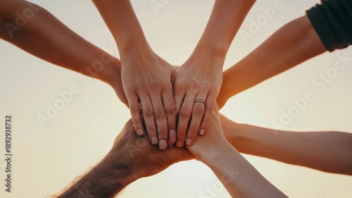 Collaborative teamwork and unity captured in symbolic hand stack against sunset