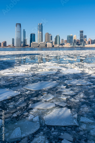 Frozen Hudson River with drifting ice floes and the skyline of downtown Jersey City, New Jersey, during extreme winter cold