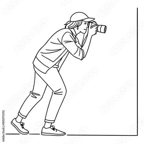 Female photographer wearing a cap crouches slightly while holding a professional camera up to her eye ready to capture an important moment with concentration and focus