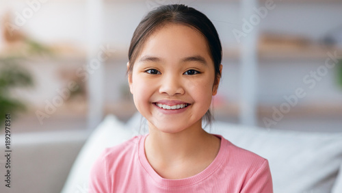 Canvas Print A young girl is sitting on a couch in a bright living room