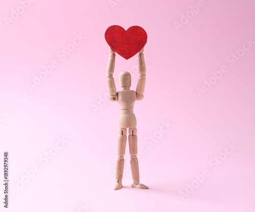 Cuadro en lienzo Wooden mannequin with red heart on pink background