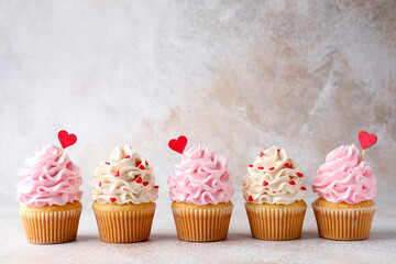 Happy Valentine's Day. Tasty cupcakes with red hearts on grey table