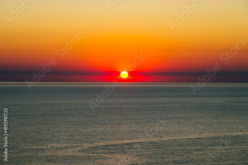 Obraz na plátně the orange sun sets over the horizon over a calm sea
