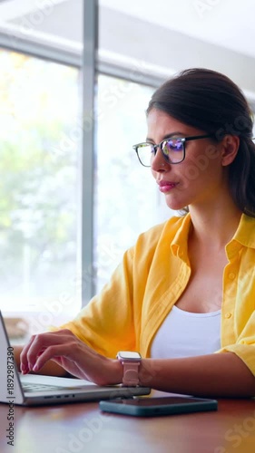 Female freelance entrepreneur working on online technological project on computer pc at company workplace. Focused young latin business woman, it specialist using laptop at work in office. Vertical