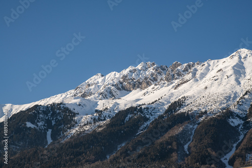 Snow-covered Nordkette mountains above Innsbruck, Austria, winter alpine panorama with clear blue sky and copy space