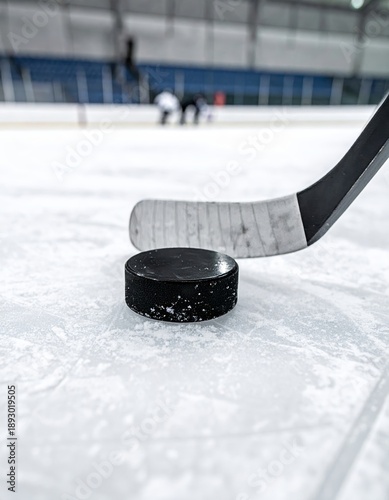  Disco de hockey sobre el hielo con un palo listo para golpear en una pista cubierta iluminada.