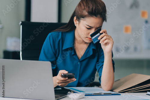 Obraz na plátně Young businesswoman is holding two credit cards with a worried expression, tryin