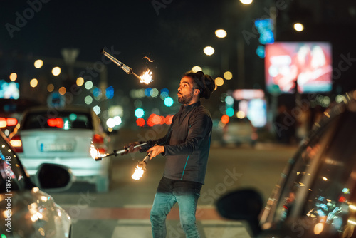 Картината върху платно Man juggling fire sticks at night city street