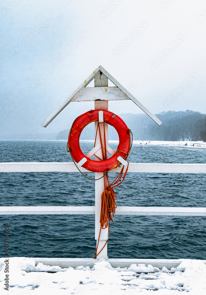 Fototapeta premium Orange lifebuoy on a wooden pier. Vacation at sea