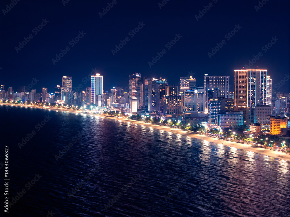 Obraz premium Aerial view Panorama of night cityscape with skyscraper neon light Nha Trang city Vietnam and bay of Sea.