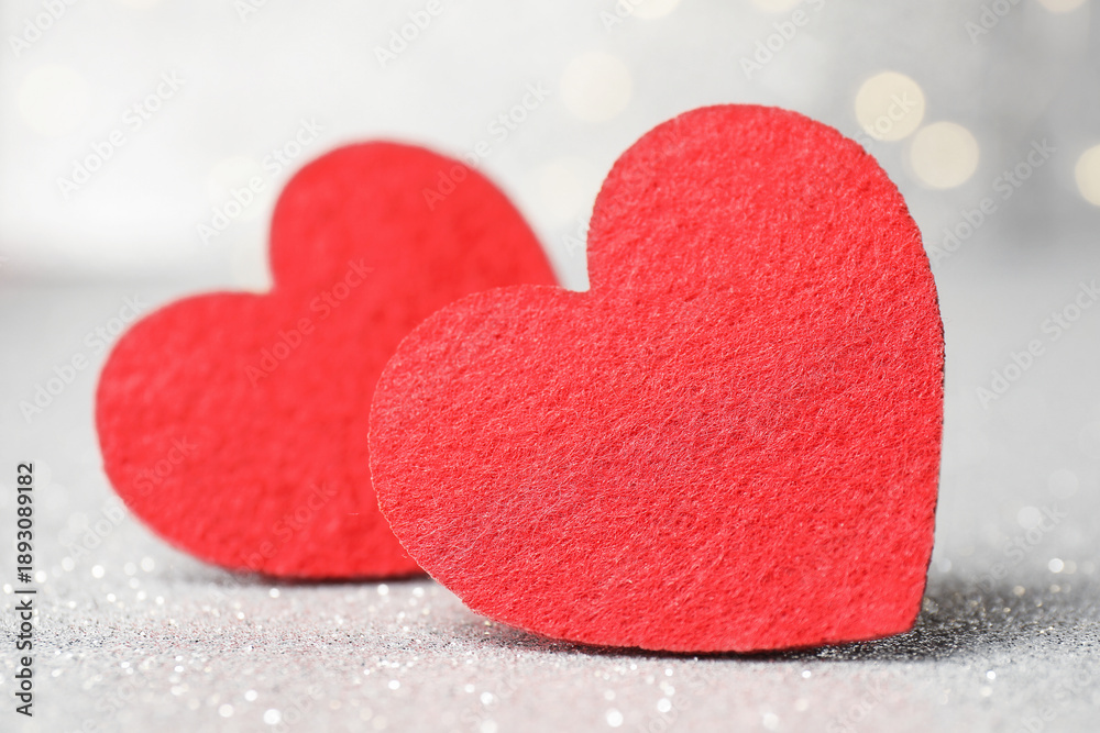 Obraz premium Love. Red decorative hearts on shiny gray surface against blurred background, closeup