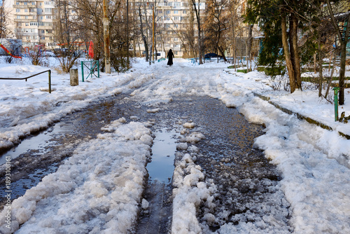 Obraz na plátně Melting snow and icy slush on residential sidewalk in early spring, wet urban pa