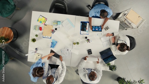 Top down view of diverse professionals collaborating in brainstorming session. Team shares medical expertise and diagnostic solutions for improved therapy at clinic.