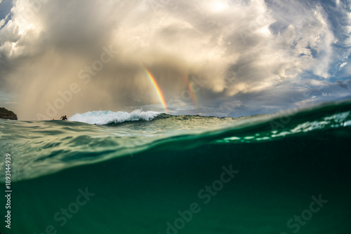 Over under ocean view with dramatic storm clouds and golden sunset light on the water surface in Sydney, Australia.