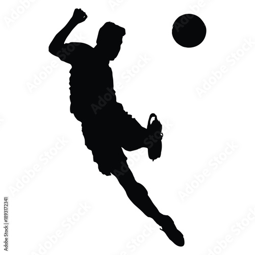 Silhouette of male soccer player kicking ball