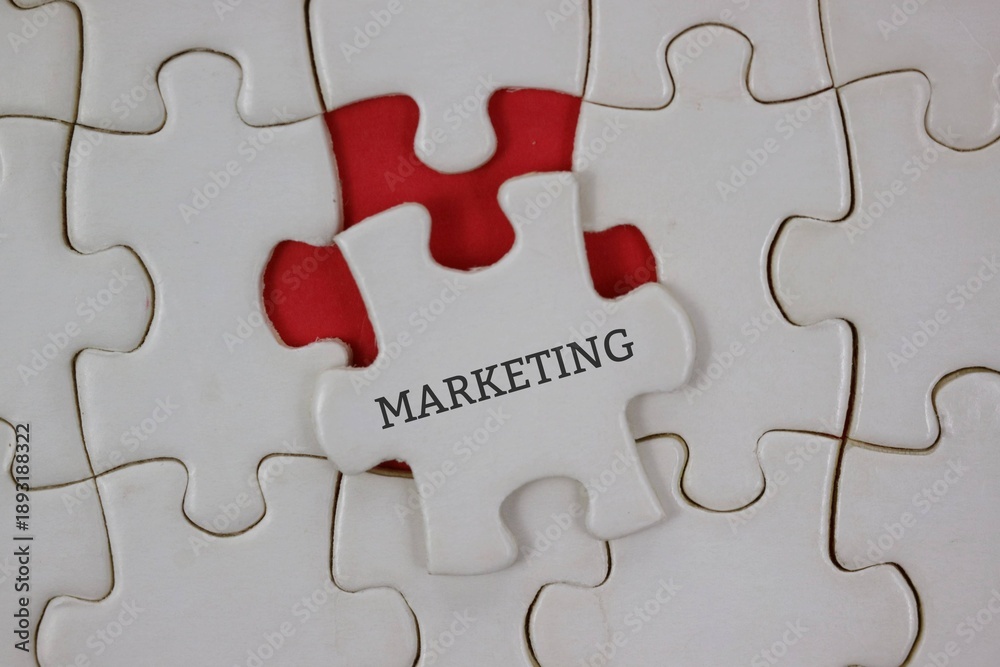 Fototapeta premium white puzzle piece labeled MARKETING sits among others on a red background, symbolizing strategic thinking and collaboration.