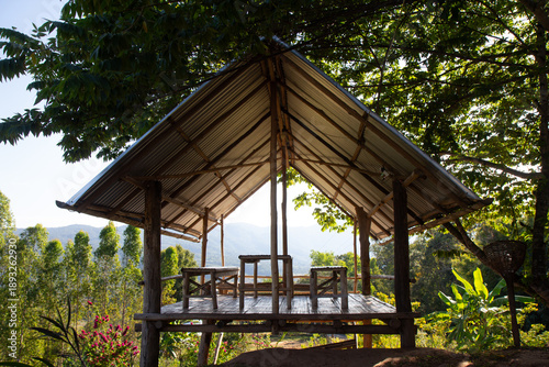 Traditional Thai wooden gazebo with a stunning mountain view at an eco-friendly resort in Northern Thailand, peaceful atmosphere for travel, relaxation, and mindfulness in a tropical forest.