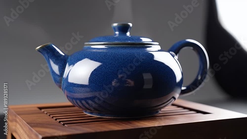 Steaming Blue Ceramic Teapot With Textured Glaze Sitting On A Wooden Tray With Soft Lighting