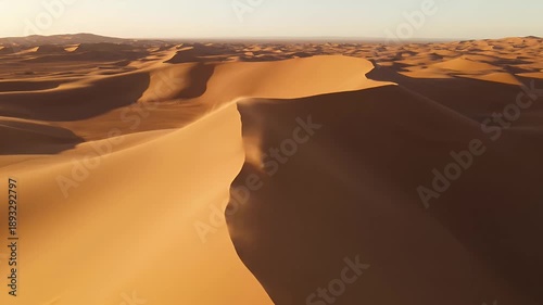 Vast Golden Desert Sand Dunes Under Warm Sunset Light With Gentle Wind And Subtle Dust Wisps Across Horizon