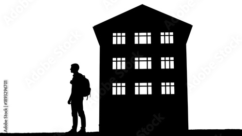 Silhouette of a person with a backpack standing in front of a building.