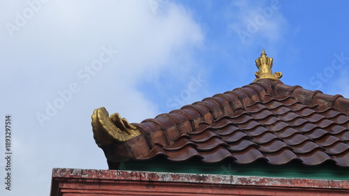 Decorations made of baked clay and golden yellow are attached to the roof of a traditional Javanese house.