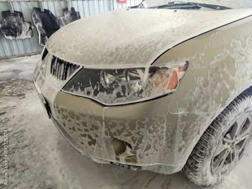 Photos Light beige SUV is completely covered in thick white foam at a car wash