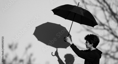 Young Man Holding Umbrella, Monochrome Shadow Play Against Wall