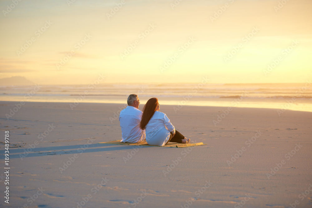 Fototapeta premium Back, love and sunset sky with couple on beach together for anniversary, bonding or relationship. Ocean, scenic view and space with mature people on sand at coast to relax for security or trust