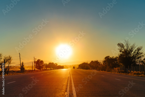 Two-lane road with sunset on the horizon