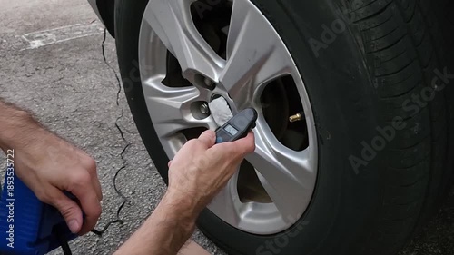 Man checking car tire pressure using electronic gauge