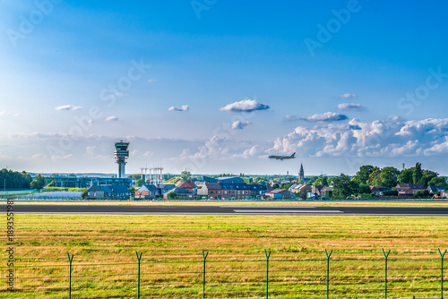 Brussels, Belgium - July 21 2023: Wide shot of an airplane on final approach to Brussels Airport with the iconic control tower and Belgian landscape