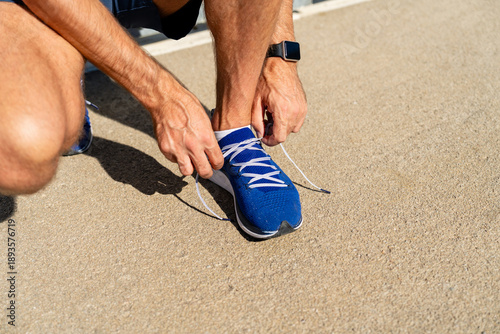 Foto Athlete lacing running shoes before training