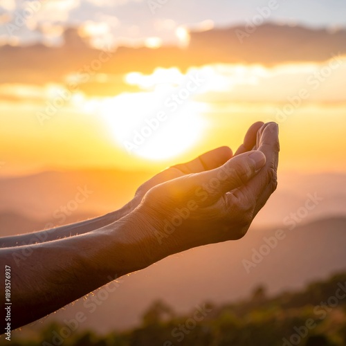 Open hands cupping warm sunlight over misty mountain backdrop