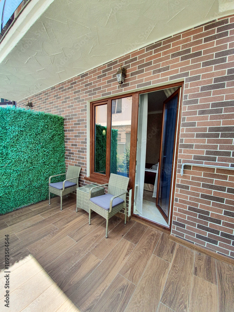 Naklejka premium Outdoor Terrace with Wicker Furniture near Brick House
