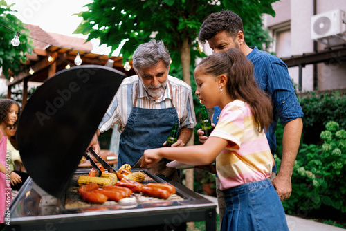 Grandfather Serving Food to Granddaughter at Family Barbecue
