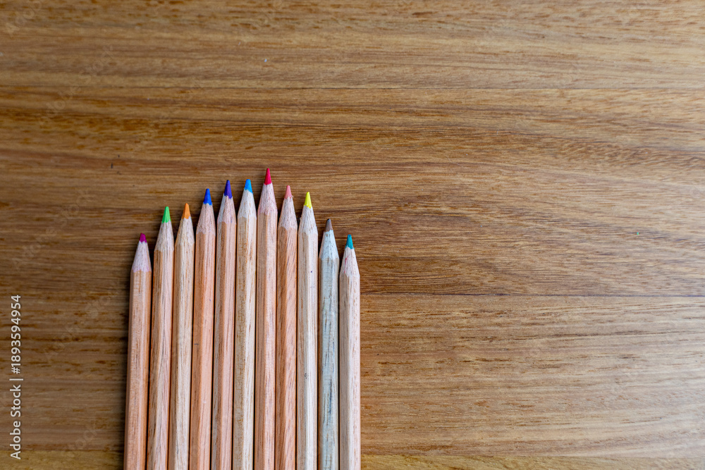 Obraz premium colorful wooden pencils arranged neatly on wooden table, symbolizing creativity, education, art supplies, and design tools for school, office, or artistic inspiration.