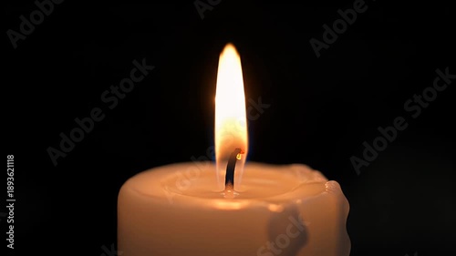 Close-up of a burning candle with a bright flame against a dark background.