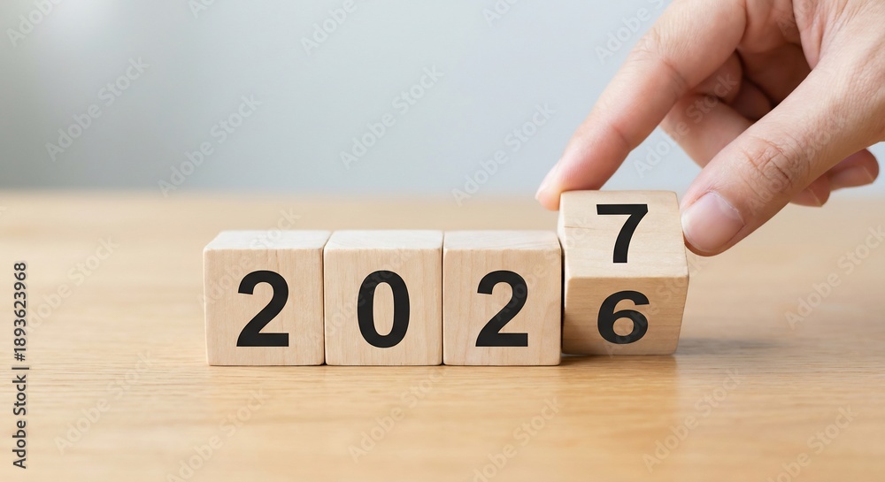 Naklejka premium Hand Flipping Wooden Block to Change Year from 2026 to 2027 on Wood Table
