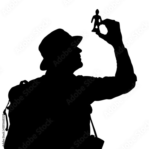 Silhouette of a Person Holding a Miniature Human Figure.