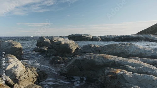 A low angle of an ocean atmosphere. the rocks kisses some low tide waves, and few seagulls passing low above the camera on a sunny spring day. a 4K video clip, Kaikoura, New Zealand.