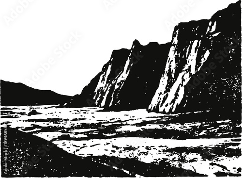 Rocky mountain cliffs with sharp peaks overlooking a flat barren landscape under clear sky