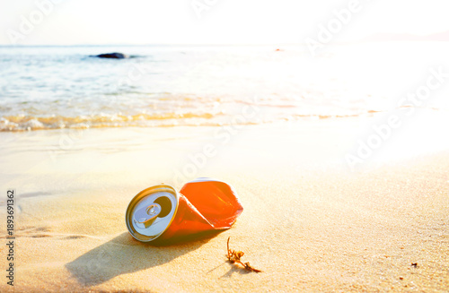 Crumpled soda can on sand beach at sea. Discarded broken soda can at seashore. Environmental pollution, sea water pollution. Rubbish on beach. Clean beach from trash. Empty crumpled can from drink.
