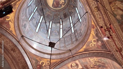 Interior view of the Patriarchal Cathedral in Bucharest, panning down from ornate ceiling frescoes and chandelier to the golden altar.