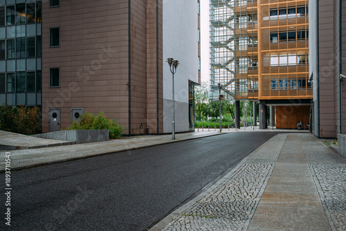 Daylight alley street corridor with empty pavement and modern urban buildings in strong perspective creating clean architectural lines and copy space