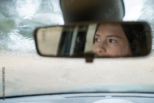 Photography Woman driver looking in rearview mirror on a rainy day