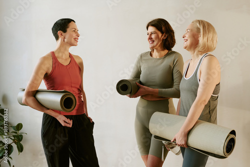 Tableau sur toile Three middle aged Caucasian women standing together holding yoga mats, smiling a