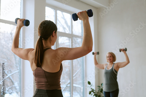 Obraz na plátne Young adult Caucasian woman and middle aged Caucasian woman exercising with dumb